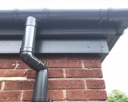 Anthracite black guttering and downpipe on a brick wall in Gloucestershire