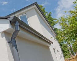 Grey guttering and downpipe on a white rendered house in Gloucestershire