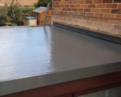 Smooth grey GRP flat roof beside a brick wall in Gloucestershire
