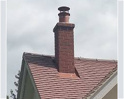 Brick chimney with a new cowl on a tiled roof in Gloucestershire