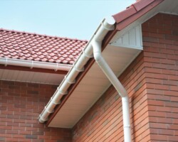 New red tile roof with white fascia and downpipe on a Gloucestershire home