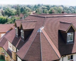 Aerial view of a re-roofed multi-gable home with new brown roof tiles in Gloucestershire