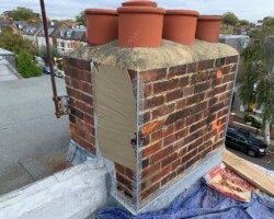 Rebuilt brick chimney with new pots and fresh flaunching in Gloucestershire