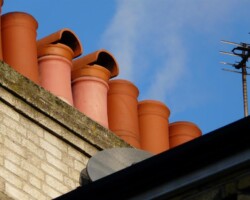 Row of terracotta chimney pots on a repointed chimney stack in Gloucestershire