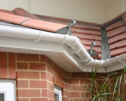 New white guttering and downpipe fitted to a brick wall in Gloucestershire